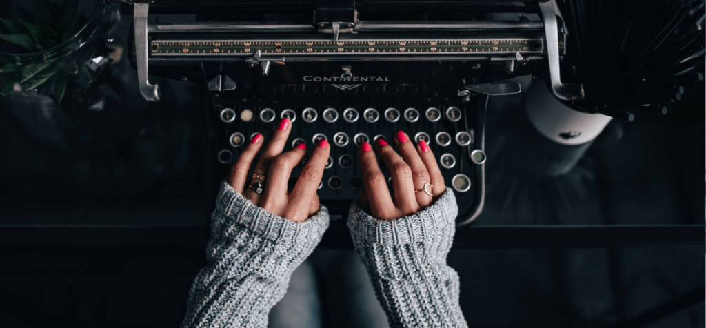 Frau mit roten Fingernägeln tippt auf einer alten Vintage Schreibmaschine