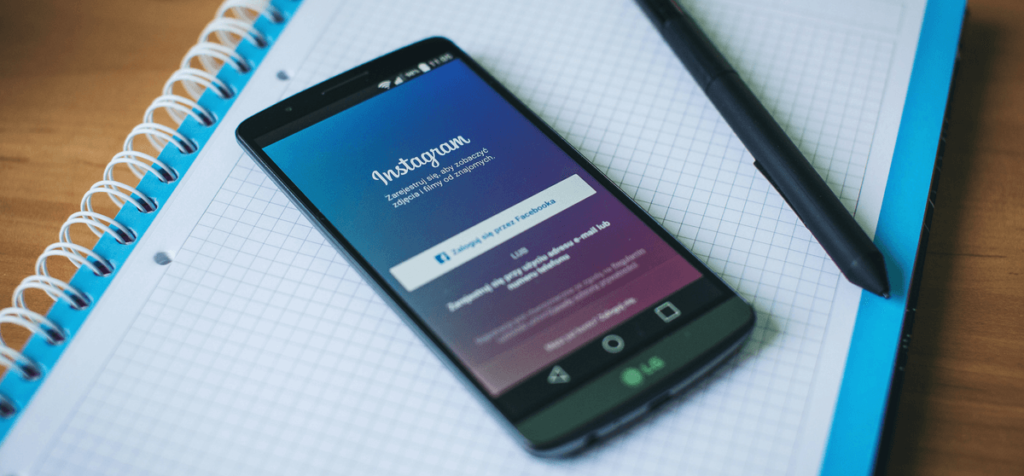 Smartphone mit offener Instagram App liegt auf Notizblock und Stift