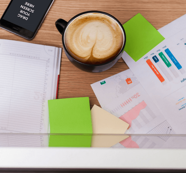Papiere und Kalender liegen auf Tisch mit Cappuccino